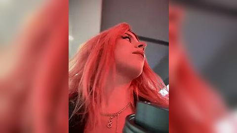 Media: A close-up video of a woman with long, vibrant pink hair, wearing a black jacket and a silver necklace, looking upward with a serene expression.