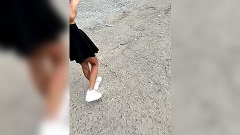 Media: A video of a young woman in a black skirt and white sneakers walking on a gravel path, partially blurred.