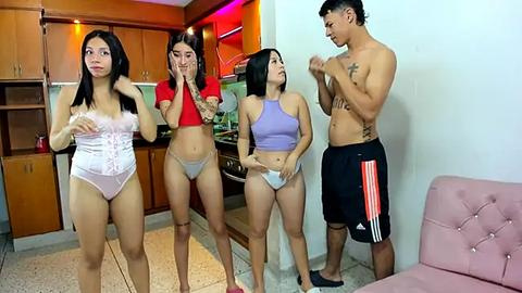 Media: Video of four young Asian women in a kitchen, surprised by a shirtless man in shorts; one wears a corset, others in sports bras and shorts.