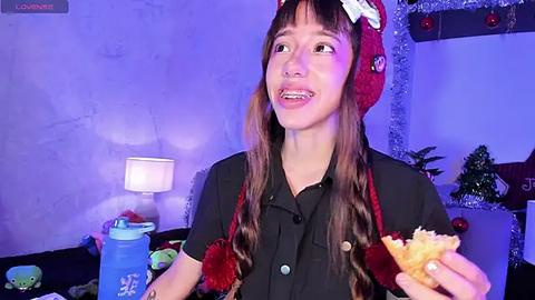 Media: A video of a smiling Asian woman with long brown hair in a red Santa hat, holding a sandwich and a blue water bottle, in a festive room with Christmas decorations.