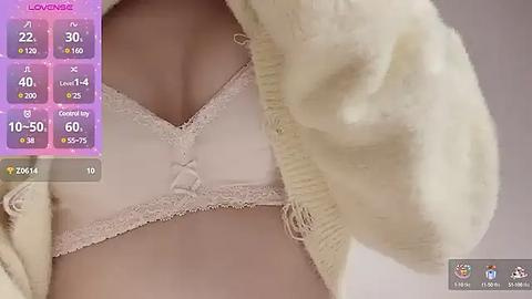 Media: Video of a woman's torso in a white lace bra and cream cardigan, with a virtual reality interface overlay showing stats and options.