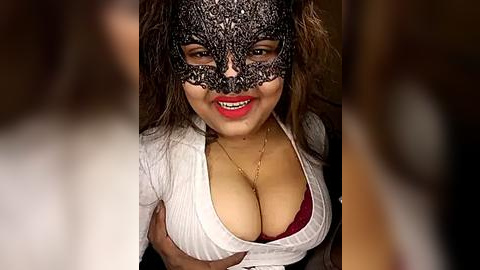 Media: Video of a woman with medium skin tone, wearing a black lace mask and white top, revealing red bra. Her long brown hair cascades around her face.