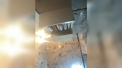 Media: Video of a kitchen with a stainless steel hood over the stove, marble countertops, and a decorative pendant light above the sink.