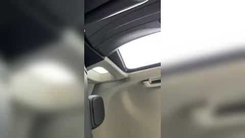 Media: A video of a car's interior, showing a sleek, modern dashboard with a large, rectangular sunroof. The cabin features a light beige color scheme, with black accents and a minimalist design.