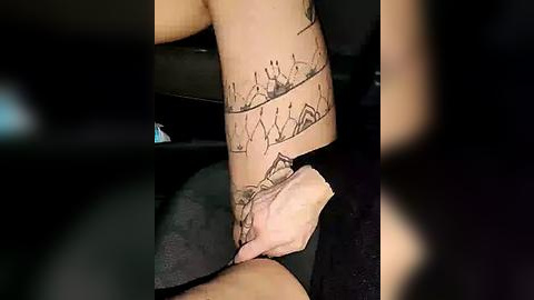 Media: Video of a person's tattooed forearm, featuring a geometric, minimalist design with black ink, set against a dark background.