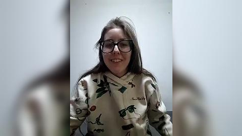 Media: Video of a smiling woman with long brown hair and glasses, wearing a festive, patterned pajama shirt, against a plain white background.