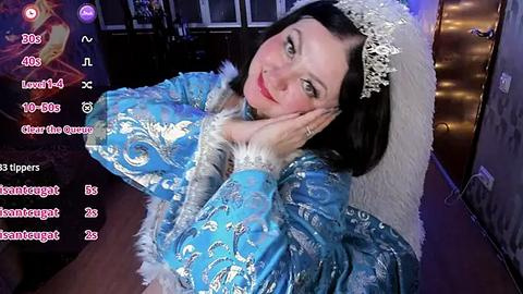 Media: A video of a fair-skinned woman with dark hair, wearing a blue and silver ornate kimono with a lace headdress, posing seductively against a dimly lit room with a soft purple glow.