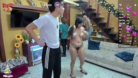 Media: In this video, a woman with large breasts and a curvy physique, wearing a thong, stands topless in a living room. A man in a white shirt and black pants watches her.