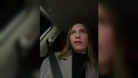 Media: A video of a blonde woman in a grey blazer, looking concerned, seated in a car with dim lighting.