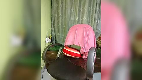 Media: A video of a messy office desk with a pink chair, green curtains, scattered papers, and a red bag, giving a disorganized and chaotic impression.