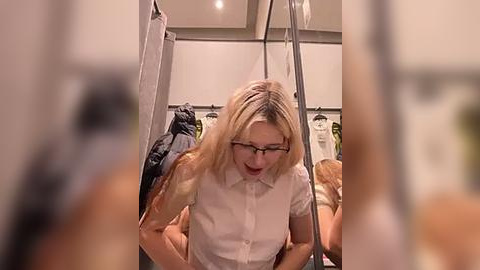 Media: A video of a blonde woman with glasses in a white blouse, leaning over a clothes rack in a dimly lit, cluttered closet.