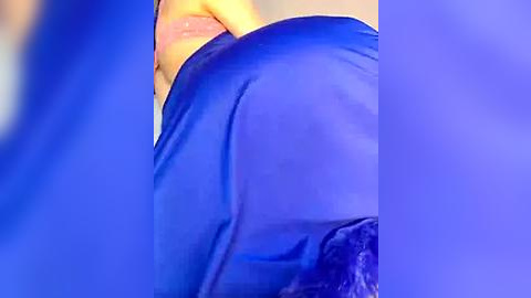 Media: A close-up video of a person wearing tight, blue spandex pants, revealing a muscular thigh and part of a bare buttock. The background is blurred, with a hint of a blue fabric texture.