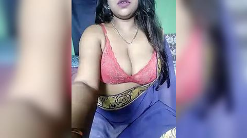 Media: A video shows a South Asian woman with medium skin tone, wearing a pink lace bra and a blue sari with a golden border, her long dark hair flowing.