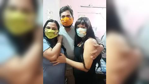 Media: Video of three people in a room, wearing masks, with blurred faces in the background, showing a casual, indoor setting.