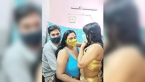 Media: Video of three people wearing masks, one in a yellow face mask, one in a blue top, and one in a yellow bikini. Background shows a pink wall and a blue tiled wall.