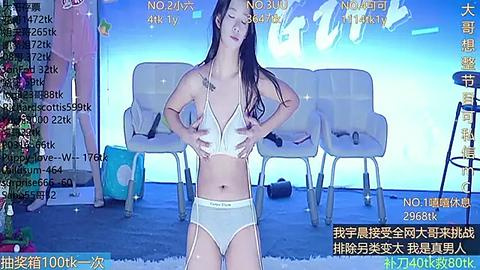 Media: Video of an Asian woman with long black hair in white Calvin Klein underwear, standing confidently in a room with a light blue background, featuring a sofa and a desk.