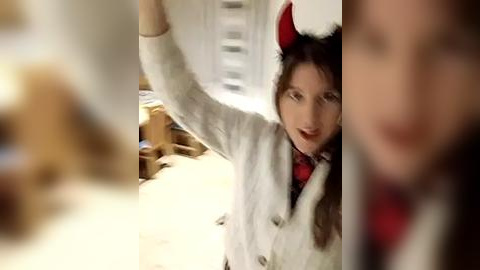 Media: A video of a young woman in a white sweater and red necktie, wearing cat ears, playfully climbing a ladder in a dimly lit room.