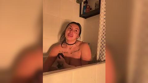 Media: Video of a young woman with fair skin, long brown hair, and a slender physique, standing naked in a tiled bathroom, wearing a black choker necklace with a tattoo on her chest.