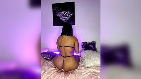 Media: Video of a curvy, dark-skinned woman with straight black hair kneeling on a bed, wearing black lingerie, with a black diamond tapestry behind her.