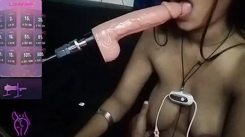 Media: Video of a nude Asian woman with medium-sized breasts, wearing a Bluetooth headset, performing oral sex on a large, realistic, flesh-colored dildo. Background includes a black chair and a digital chart displaying sexual statistics.