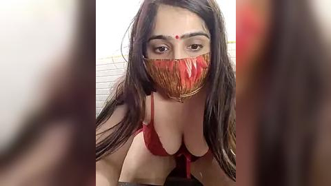 Media: A video of a South Asian woman with long dark hair, wearing a red bikini and a red face mask, in a tiled bathroom, blurry background.