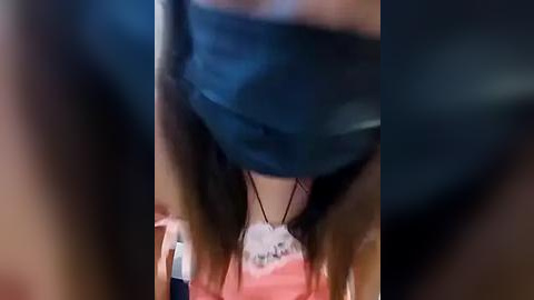 Media: A blurry, low-resolution video of a person's face and neck, wearing a blue mask and a white shirt, with blurred background.