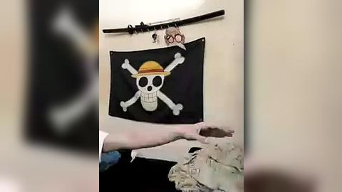 Media: Video of a person holding a black flag with a skull and crossbones design, with a stuffed monkey on a wooden stick above.