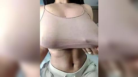 Media: Video of a woman with fair skin, wearing a sheer, pink tank top that reveals her large, erect nipples and a flat stomach. She has on white, loose-fitting pants. The background is blurred.