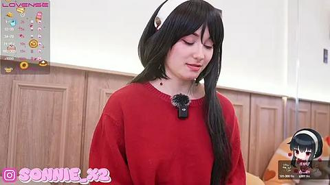 Media: Video of a young woman with long black hair, wearing a red sweater, and a white headband, standing against a wooden-paneled wall. The image includes a watermark and a small chibi avatar in the bottom right.