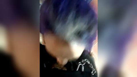 Media: Blurry video of a person with short, spiky blue hair, wearing a black jacket with white patches, partially obscured by motion blur.