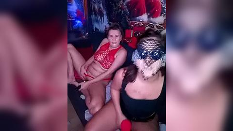 Media: Video of a fair-skinned woman in red lingerie and a brunette woman in a blue knit hat, engaged in oral sex on a man with a visible erection, set in a dimly lit room with Christmas decor.