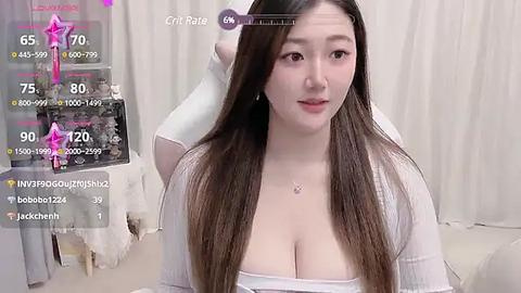 Media: Video of an East Asian woman with long brown hair, wearing a white top, in a white room, overlaid with virtual reality game elements.