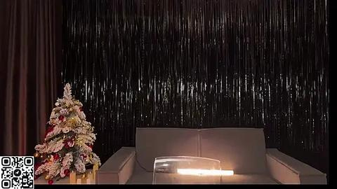 Media: A video of a modern living room with a Christmas tree adorned with white and red flowers, set against a dark, shiny curtain backdrop.