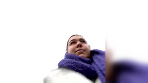 Media: Video of a young Asian woman with short black hair, wearing a purple blanket, looking up at the sky with a contemplative expression.