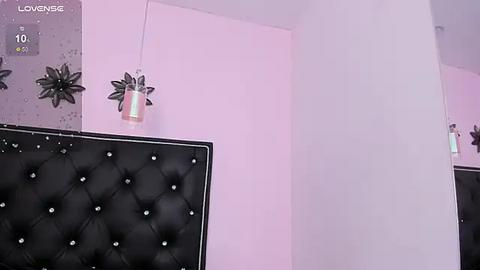 Media: A video of a minimalist, pastel-colored bedroom with a black tufted headboard, light pink walls, and modern, geometric wall art. A small, silver lamp hangs from the ceiling.