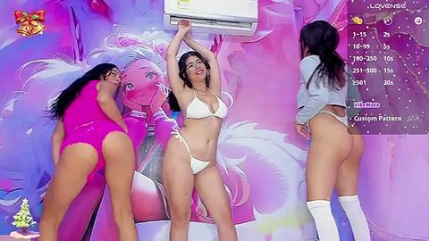 Media: Video of three women in revealing bikinis, standing in a vibrant, pink-themed room with a Disney Princess mural. One woman is lifting her arms, smiling, while the others pose provocatively.