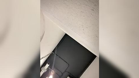 Media: Video of a ceiling with a visible gap where a black, rectangular piece of drywall has been removed, exposing white textured plaster.