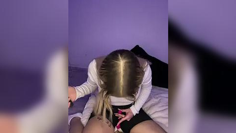 Media: Video of a blonde woman with braided hair performing oral sex on a man lying on a bed, purple lighting.