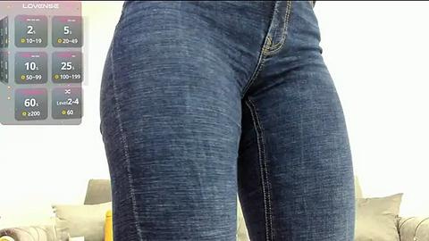 Media: A close-up video of a woman's denim-clad thighs, showcasing a colorful fitness app interface displaying her progress. The background features a beige sofa and a blurred living room.