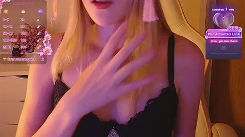 Media: Video of a blonde woman with fair skin, wearing a black lace bra, sitting in a yellow leather chair, with a purple chat box on screen.