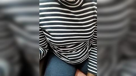 Media: Video of a person wearing a black and white striped sweater, with blurred background, highlighting the textured fabric and casual style.