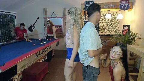 Media: Video of a cozy pool hall with four people, including a blonde woman in a red top, playing pool.