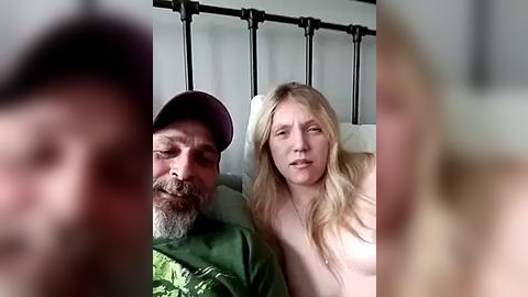 Media: A video of a man with a beard and a woman with long blonde hair, both in bed, blurry faces, soft lighting.