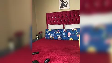 Media: Video of a cozy bedroom with a red tufted headboard, blue unicorn-themed bedding, red carpet, and a red teddy bear on a nightstand.