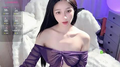 Media: Video of an East Asian woman with long black hair, fair skin, and a slender physique. She wears a sheer, purple off-shoulder top, revealing her small breasts. The background features a white fluffy blanket and a grey dresser.