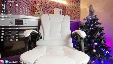 Media: Video of a modern kitchen with a white ergonomic chair, silver oven, purple accent wall, and a decorated Christmas tree.