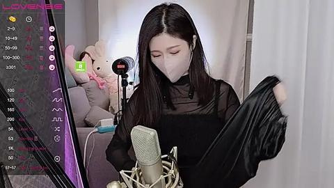 Media: A video of an East Asian woman with long black hair, wearing a black mask, singing into a microphone, surrounded by plush toys and a virtual reality headset.