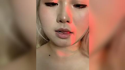 Media: Video of a young Asian woman with light skin, wet hair, and red lighting, focusing on her lips and nose, with blurred background.