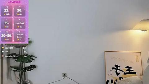 Media: Video of a minimalist living room with a large, purple digital display showing a weather forecast, a green plant, and a modern abstract painting on the wall.