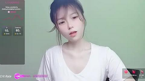 Media: A video of a young East Asian woman with fair skin and dark hair, wearing a white top, against a plain green background.